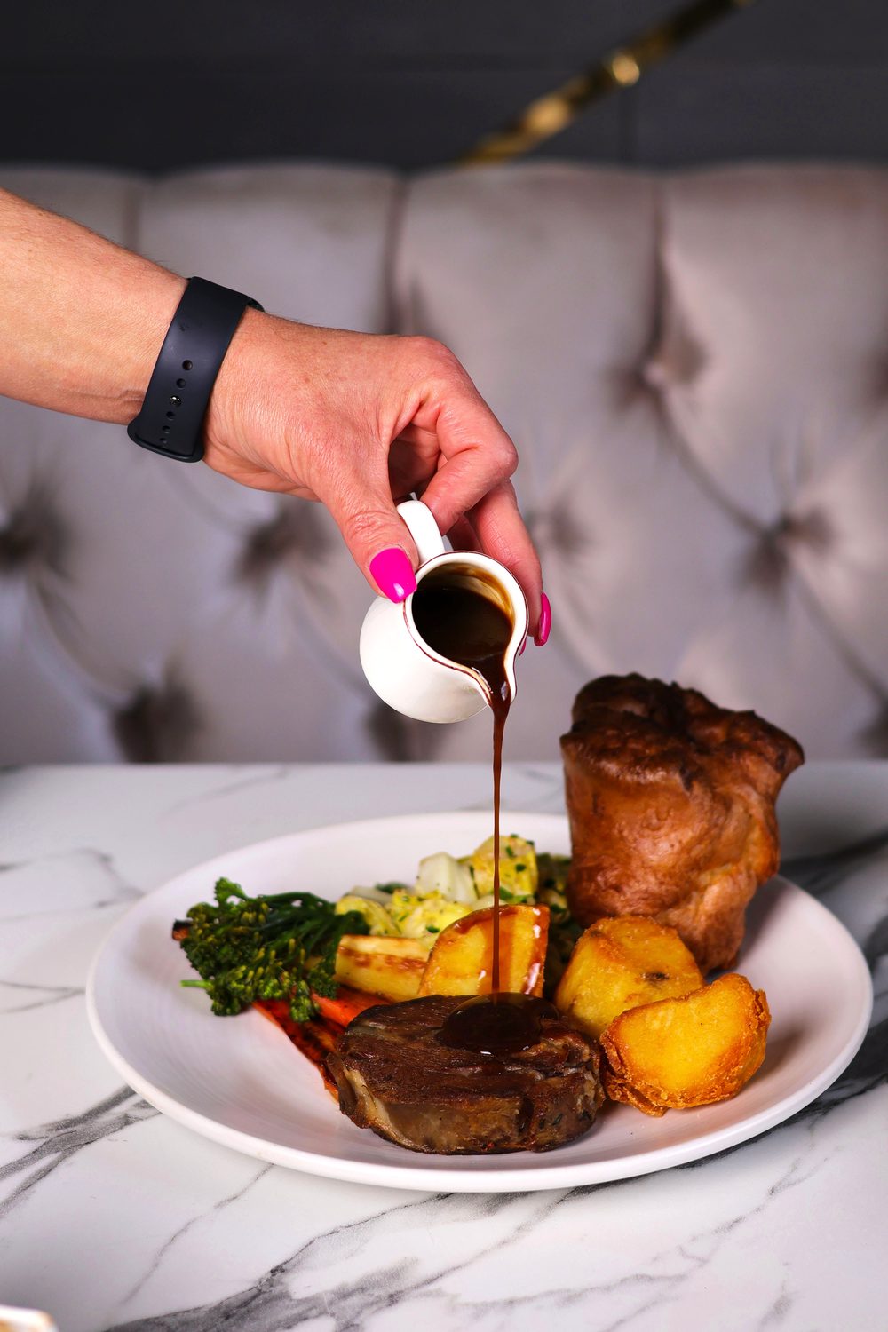 Gravy being poured over a Sunday roast with Yorkshire pudding
